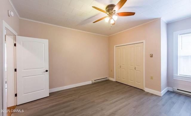 unfurnished bedroom featuring crown molding, hardwood / wood-style flooring, and baseboard heating