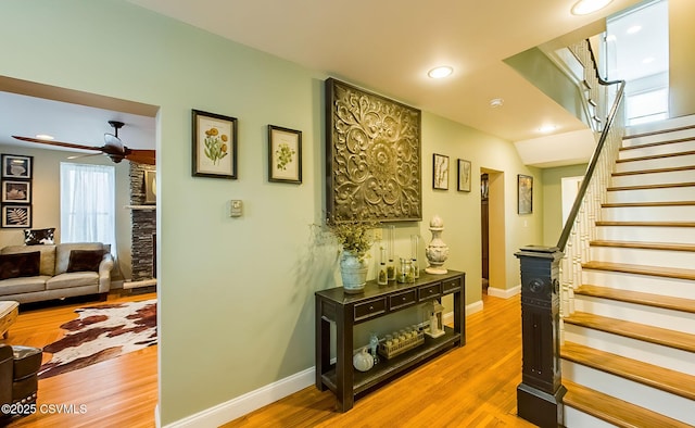 staircase with hardwood / wood-style floors and ceiling fan