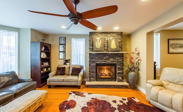 living room with a fireplace, light hardwood / wood-style floors, and ceiling fan