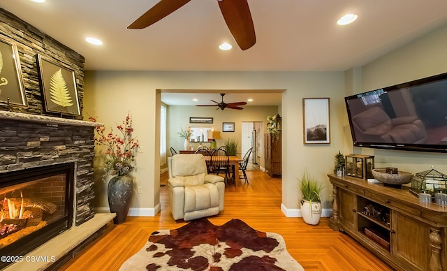 living room with ceiling fan and a stone fireplace