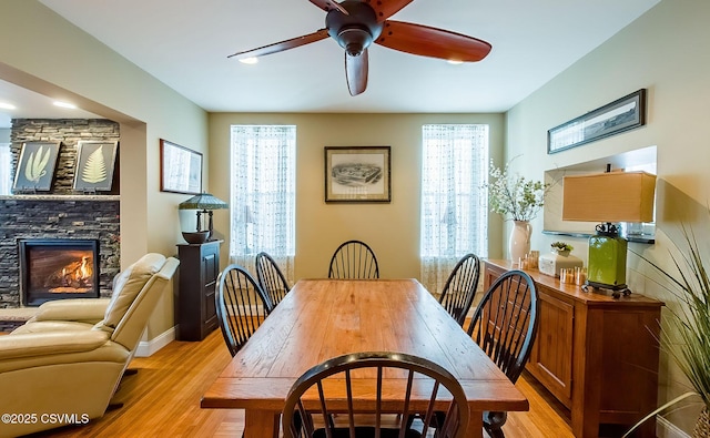 dining area with a stone fireplace, plenty of natural light, and light wood-type flooring