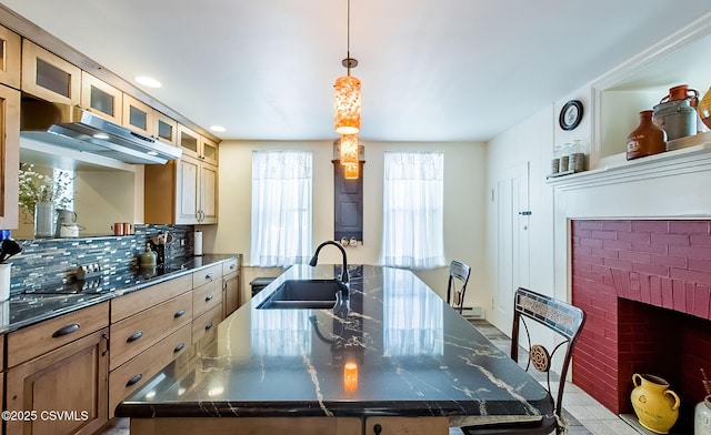 kitchen featuring decorative light fixtures, sink, dark stone counters, and a spacious island