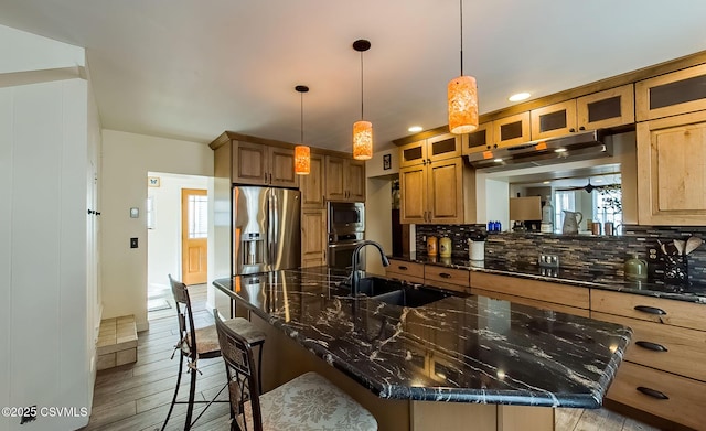 kitchen featuring sink, a breakfast bar, appliances with stainless steel finishes, tasteful backsplash, and dark stone counters