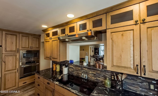 kitchen featuring appliances with stainless steel finishes, backsplash, dark hardwood / wood-style flooring, and dark stone counters