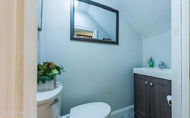 bathroom featuring vanity, toilet, and vaulted ceiling