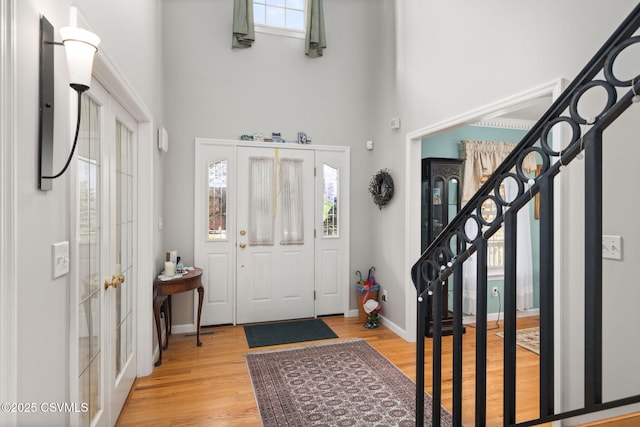 foyer entrance with a high ceiling, light hardwood / wood-style floors, and french doors