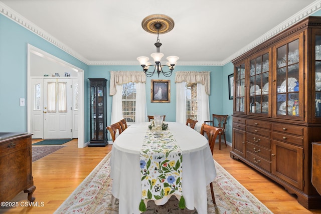 dining area featuring crown molding, light wood-type flooring, and a chandelier