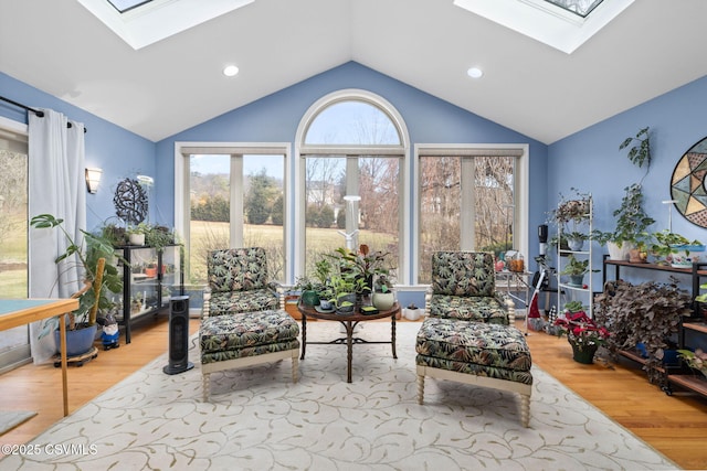 sitting room featuring lofted ceiling with skylight and light wood-type flooring