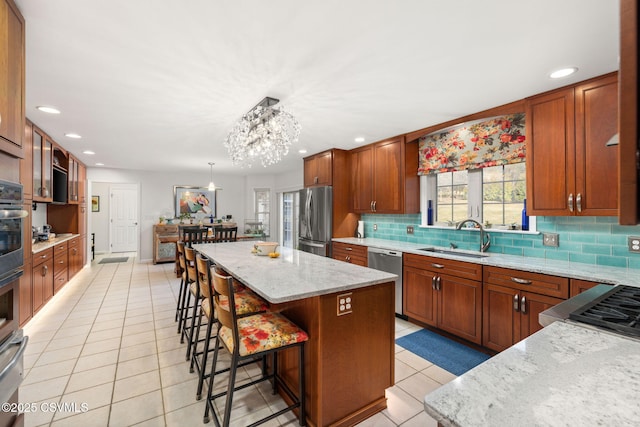 kitchen with pendant lighting, sink, stainless steel appliances, a center island, and light tile patterned flooring