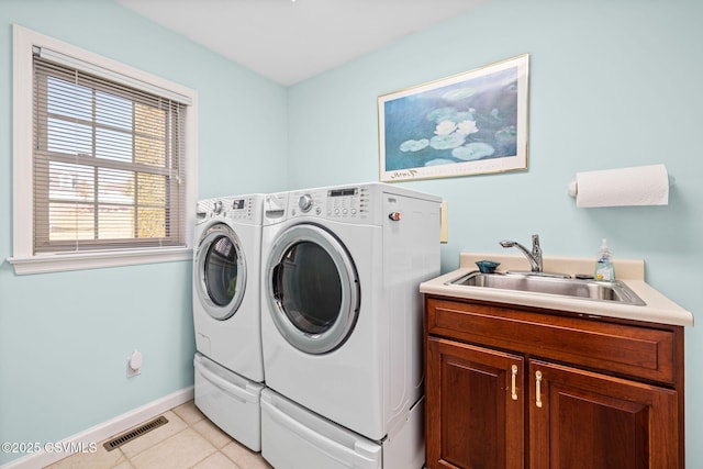 washroom featuring sink, light tile patterned floors, washer and clothes dryer, and cabinets