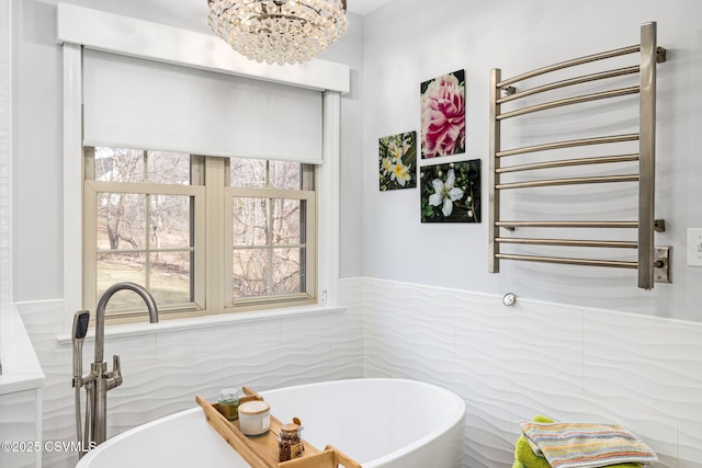 bathroom featuring a washtub, a notable chandelier, radiator heating unit, and tile walls