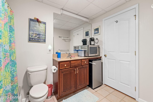 bathroom featuring vanity, a paneled ceiling, tile patterned floors, and toilet