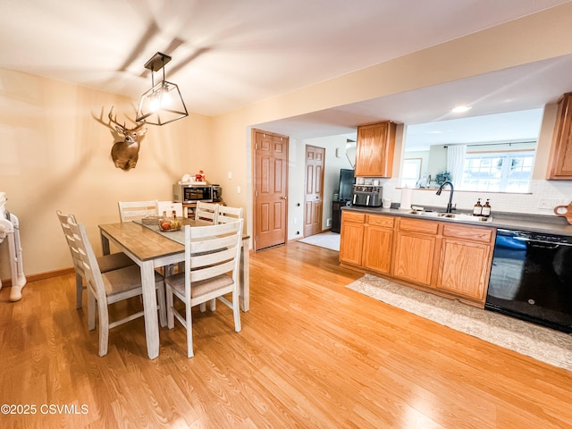 kitchen with pendant lighting, sink, black dishwasher, and light wood-type flooring