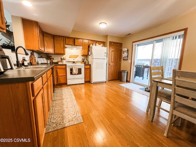 kitchen with sink, white appliances, and light hardwood / wood-style flooring