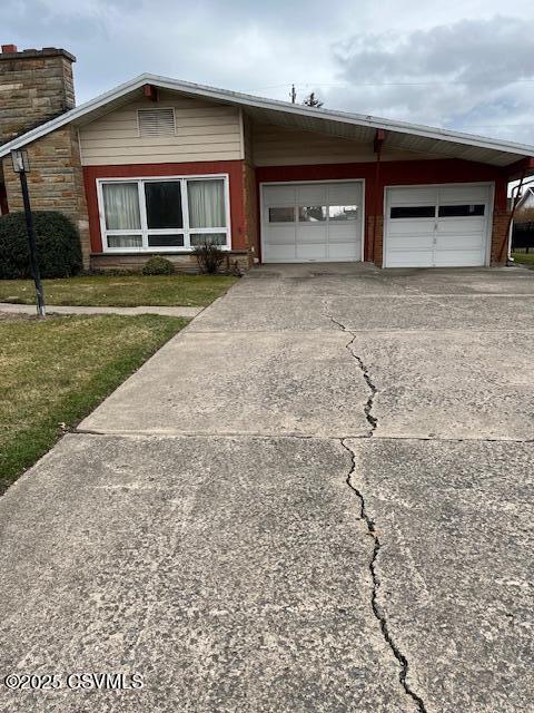 view of front of house featuring a front yard, concrete driveway, and a garage