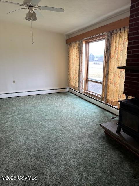 unfurnished living room with a ceiling fan, a wood stove, and carpet