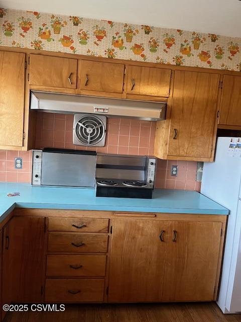 kitchen featuring freestanding refrigerator, wallpapered walls, and light countertops