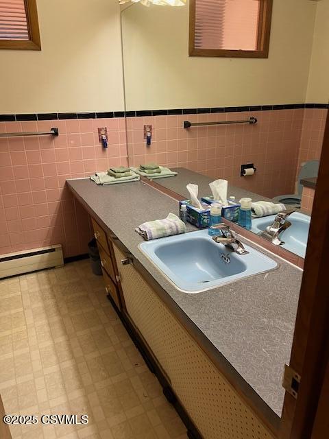 bathroom featuring tile walls, a wainscoted wall, a baseboard radiator, tile patterned floors, and vanity