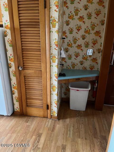 interior details with freestanding refrigerator, wallpapered walls, and wood finished floors