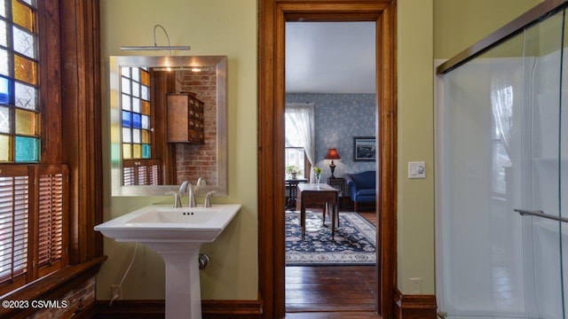 bathroom with wood-type flooring, an enclosed shower, and sink