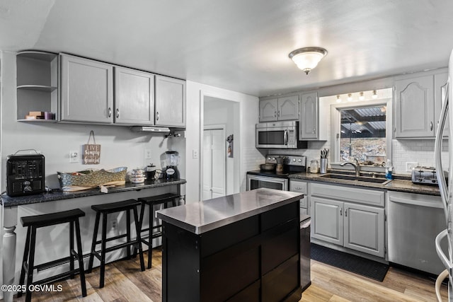 kitchen with stainless steel appliances, tasteful backsplash, sink, and light hardwood / wood-style flooring