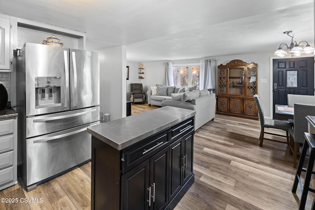 kitchen with light hardwood / wood-style flooring, stainless steel fridge, an inviting chandelier, a center island, and tasteful backsplash