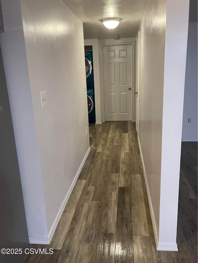 hall featuring stacked washer / drying machine and dark hardwood / wood-style flooring