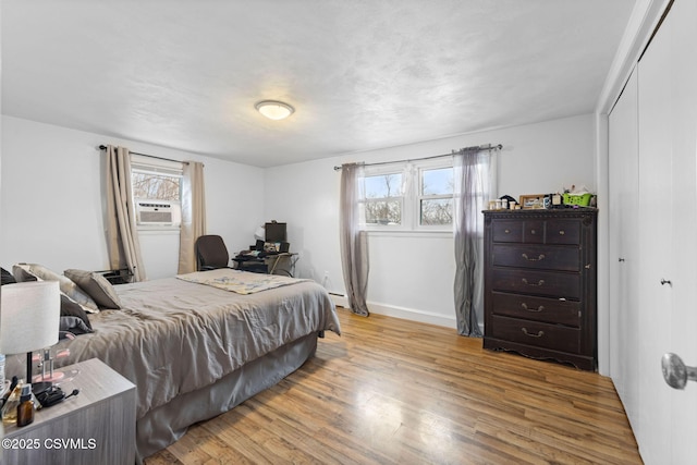 bedroom featuring cooling unit, a closet, multiple windows, and light wood-type flooring