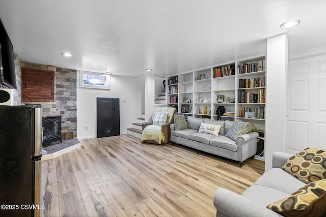 living room with a wood stove and light wood-type flooring