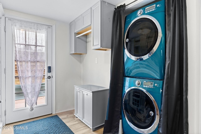 laundry room with stacked washing maching and dryer and light hardwood / wood-style floors