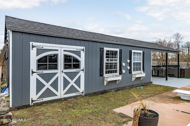 view of outbuilding with a hot tub and a yard