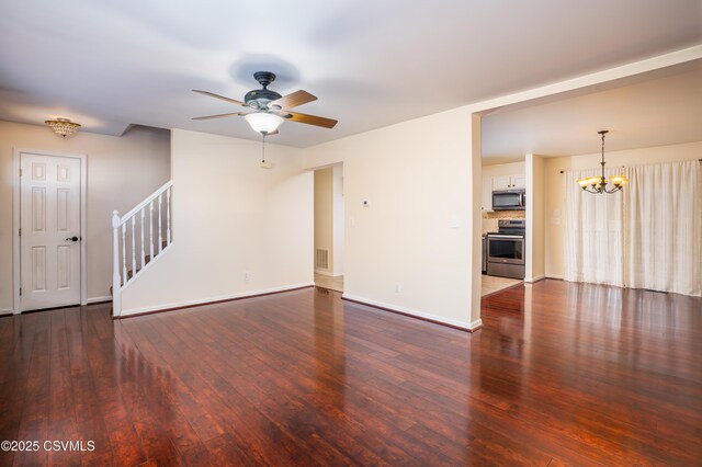 unfurnished living room with visible vents, baseboards, stairs, ceiling fan with notable chandelier, and wood-type flooring