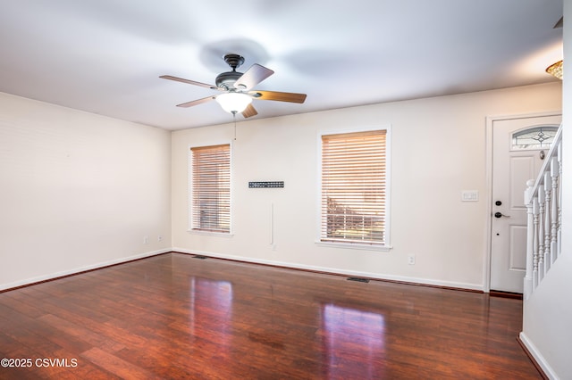 empty room with stairs, plenty of natural light, wood finished floors, and baseboards