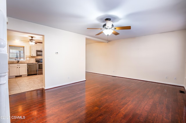 unfurnished living room with visible vents, baseboards, wood-type flooring, and a sink