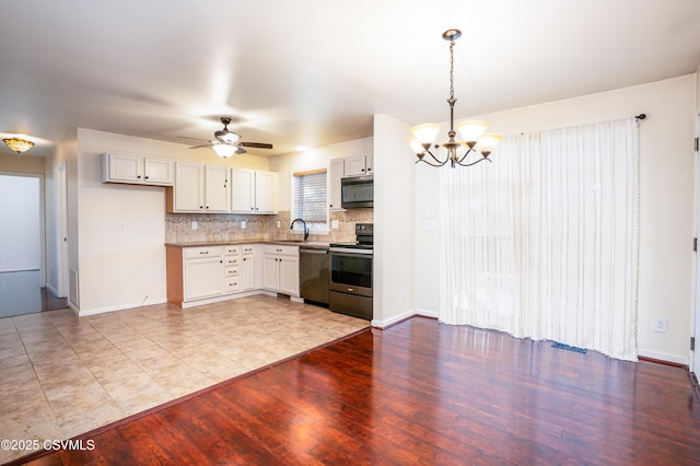 kitchen with light wood-type flooring, a sink, tasteful backsplash, stainless steel appliances, and hanging light fixtures