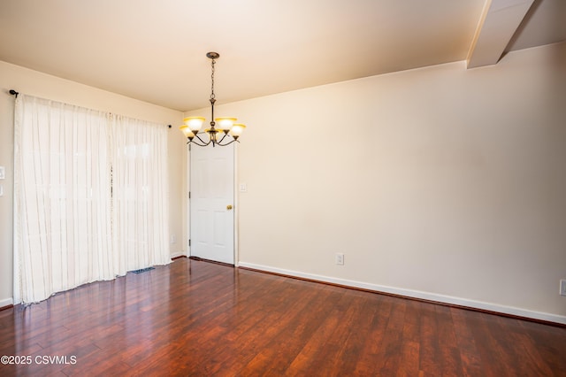 empty room with a chandelier, baseboards, and wood finished floors