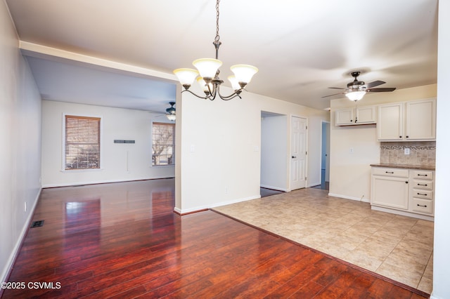 kitchen featuring backsplash, baseboards, open floor plan, light wood-type flooring, and white cabinetry