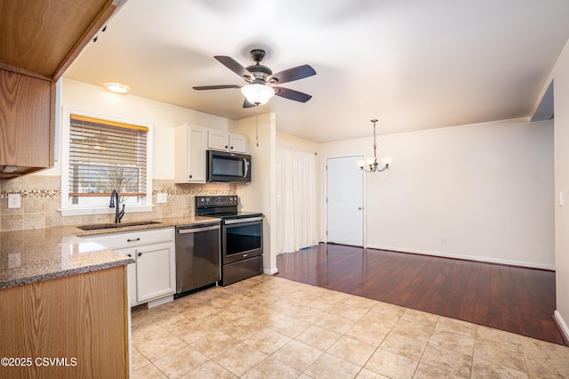 kitchen with light stone counters, decorative backsplash, appliances with stainless steel finishes, white cabinets, and a sink