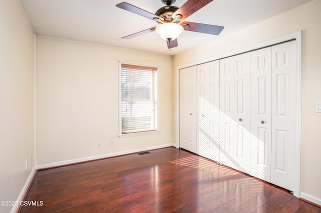 unfurnished bedroom featuring visible vents, ceiling fan, baseboards, wood finished floors, and a closet