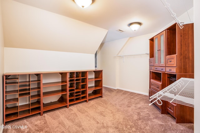 interior space featuring visible vents, lofted ceiling, and carpet