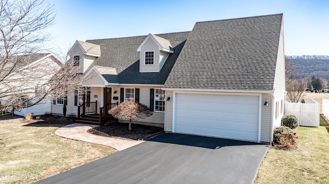 cape cod-style house featuring driveway, fence, a front yard, a shingled roof, and a garage