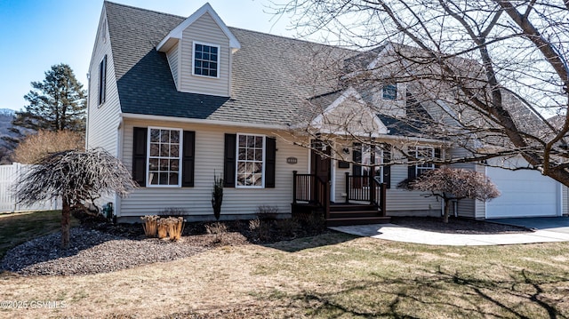 new england style home with a front lawn, a garage, and a shingled roof