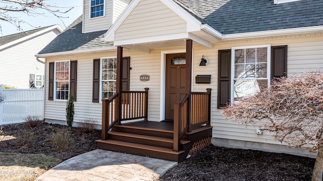 property entrance with fence and a shingled roof