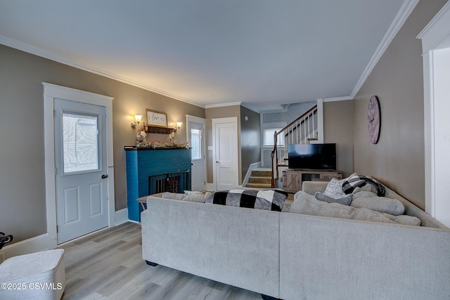 living area featuring light wood-style floors, a wealth of natural light, a fireplace, and stairs