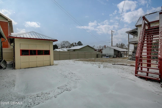 yard layered in snow featuring a garage, fence, and an outdoor structure