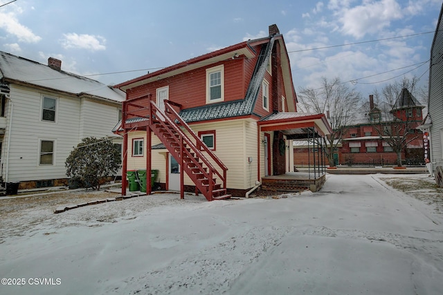 exterior space with stairs, a chimney, and a gambrel roof