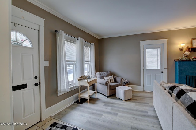 entrance foyer featuring baseboards, a brick fireplace, light wood-style flooring, and crown molding