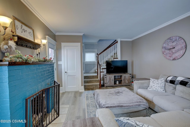 living area featuring ornamental molding, a fireplace, stairway, and light wood finished floors