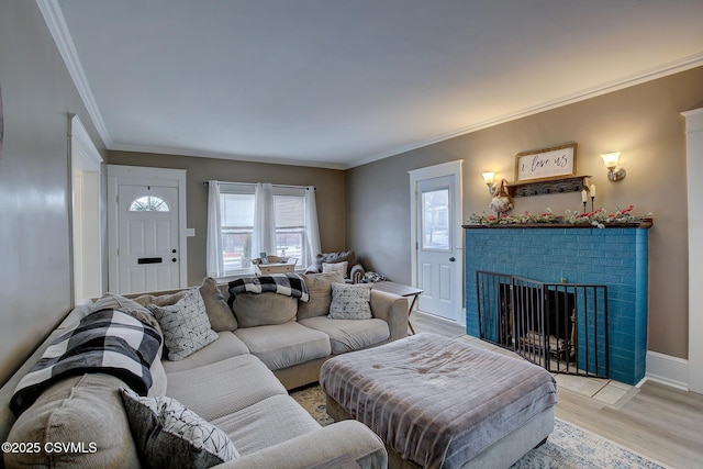 living area with light wood-type flooring, a brick fireplace, baseboards, and crown molding