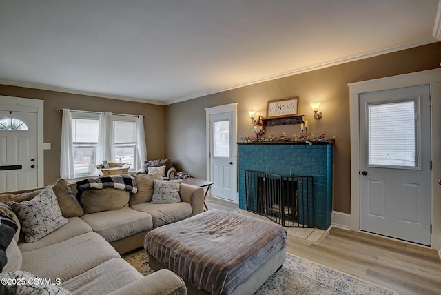 living room with baseboards, light wood-type flooring, a fireplace, and crown molding